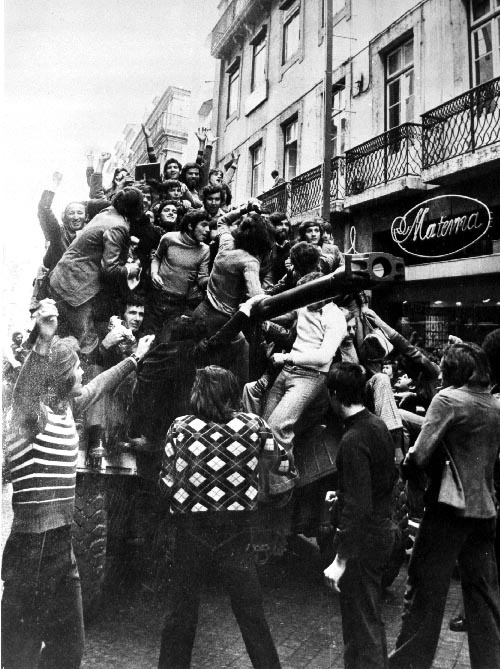 Centro de Documentação 25 de Abril, CC BY 4.0 <https://creativecommons.org/licenses/by/4.0>, via Wikimedia Commons Portugiesinnen und Portugiesen erklimmen während der Nelkenrevolution einen Panzer.
